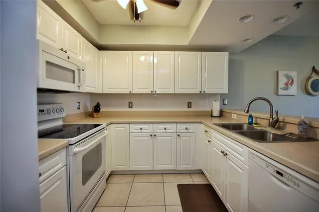 a kitchen with granite countertop white cabinets and white appliances
