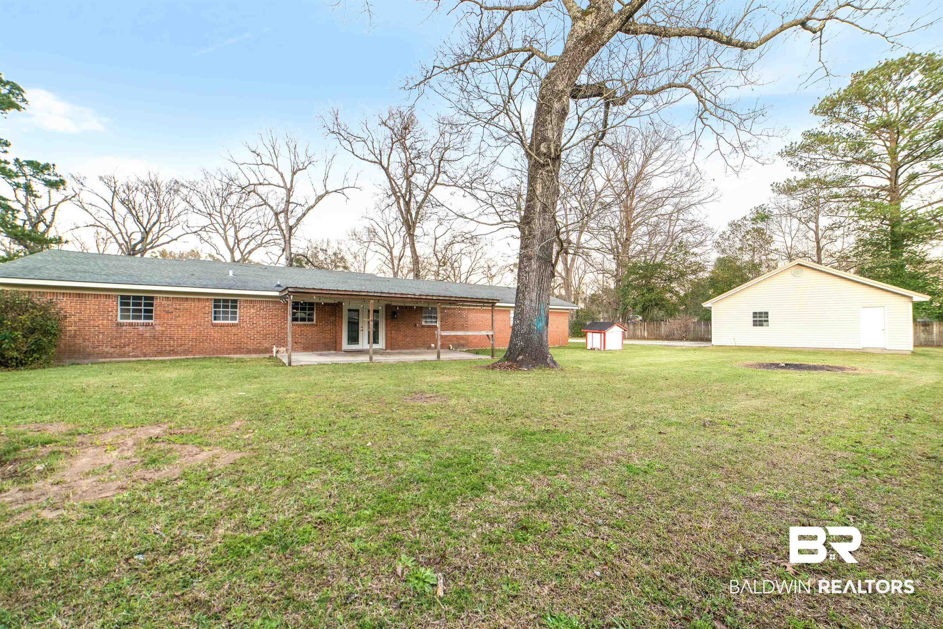 11833 Old Moffat Road Wilmer, AL 36587 - Photo 16 of 23 Back of property with a storage shed, brick siding, an outdoor structure, a lawn, and a patio area