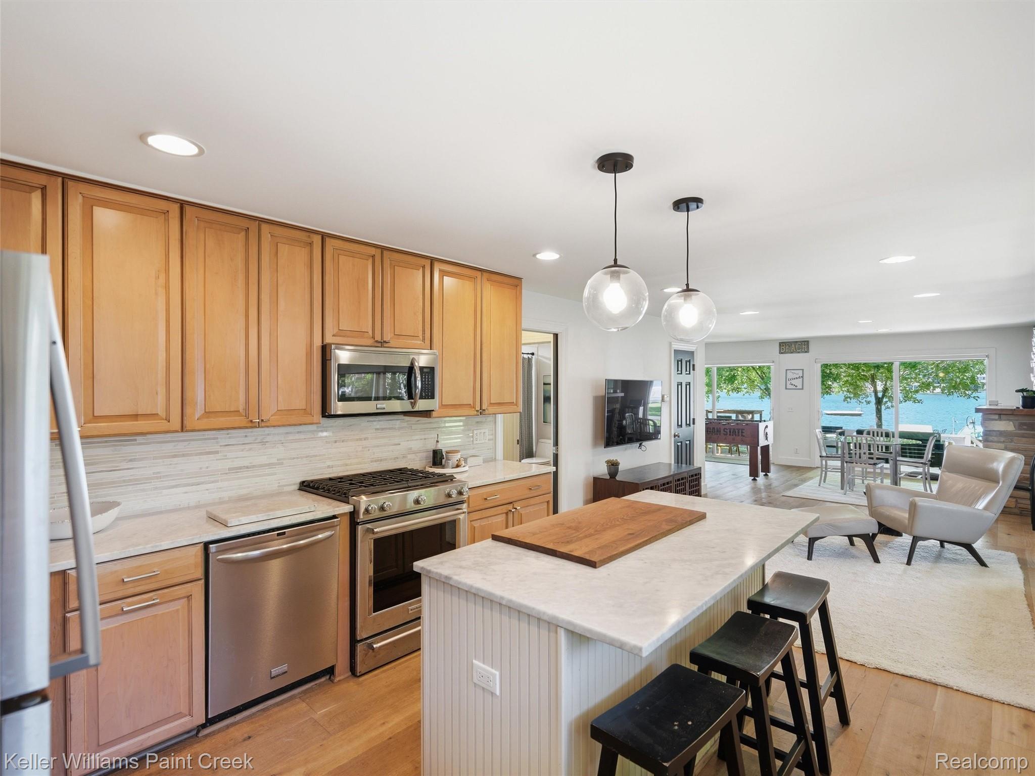 10435 Spring Street Fenton, MI 48430 - Photo 12 of 40 Kitchen featuring light wood cabinetry, stainless steel appliances, a white tile backsplash, and a central island with a light-toned countertop