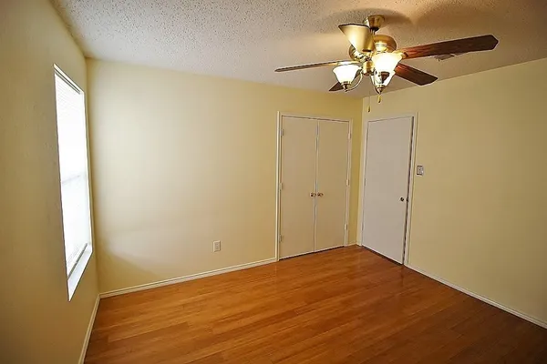 a view of a big room with wooden floor and chandelier fan