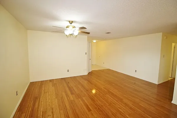 a view of a big room with wooden floor and a chandelier fan