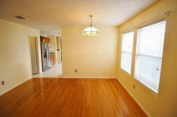 a view of an empty room with window and wooden floor