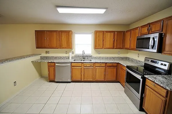 a kitchen with stainless steel appliances granite countertop a stove a sink and a microwave