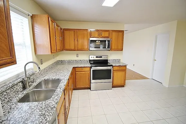 a kitchen with stainless steel appliances granite countertop a sink a stove a microwave a counter top space and cabinets