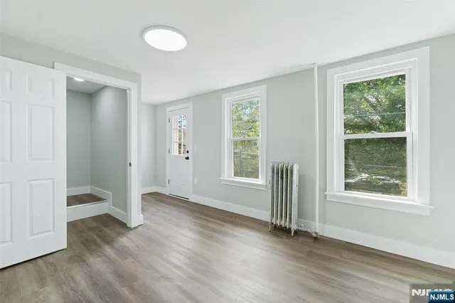 an empty room with wooden floor and windows