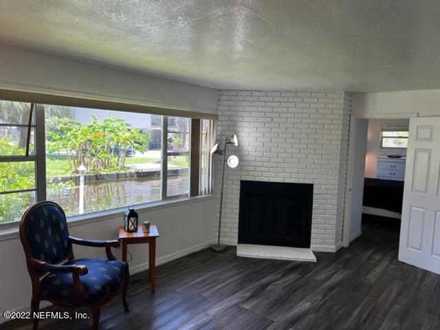 7222 Tropical Drive Weeki Wachee, FL 34607 - Photo 4 of 26 a living room with furniture a fireplace and a floor to ceiling window