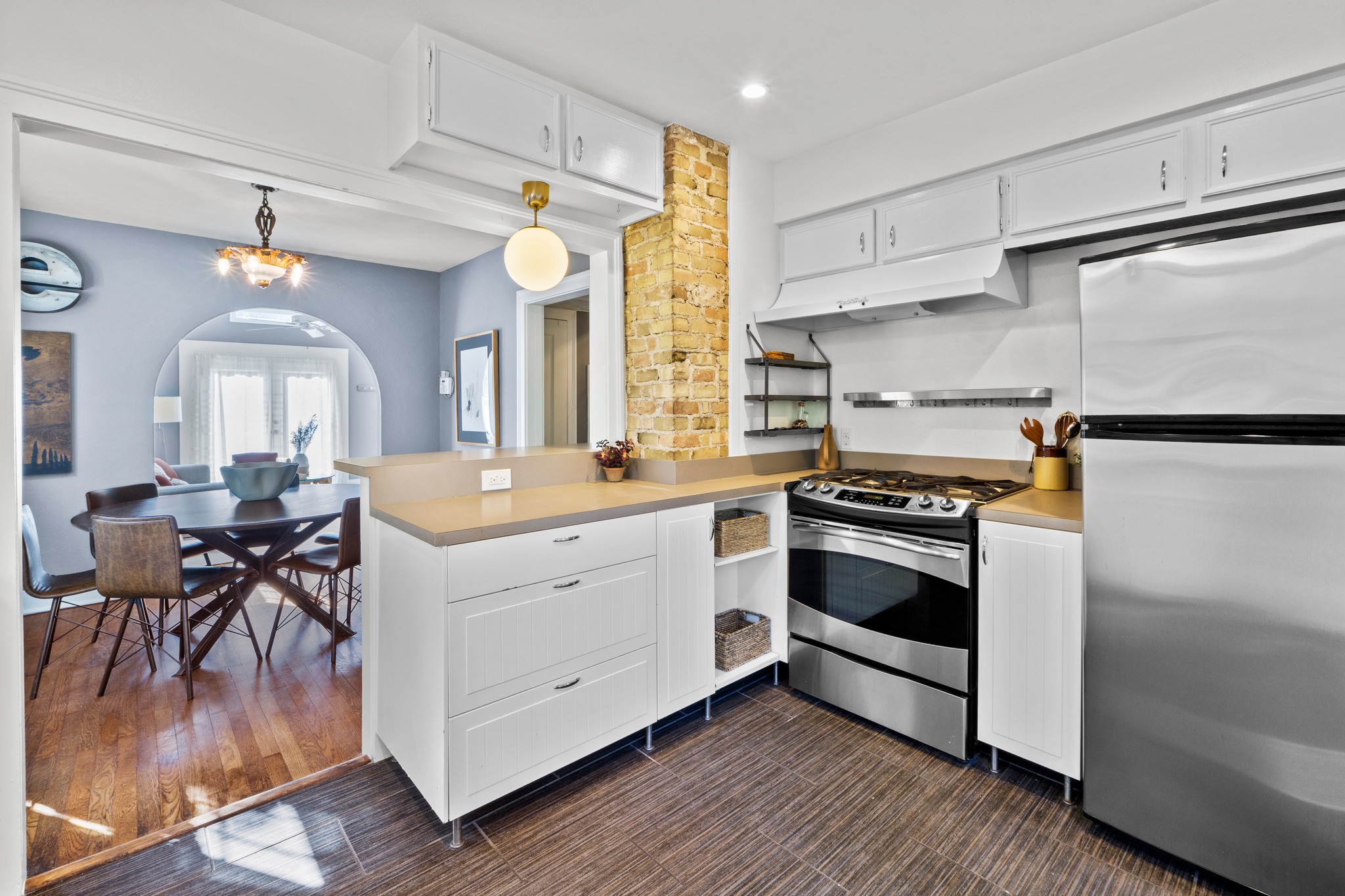 4802 Rowena Avenue Austin, TX 78751 - Photo 11 of 37 Modern kitchen featuring stainless steel appliances, white cabinetry, integrated range hood, and a light-toned countertop