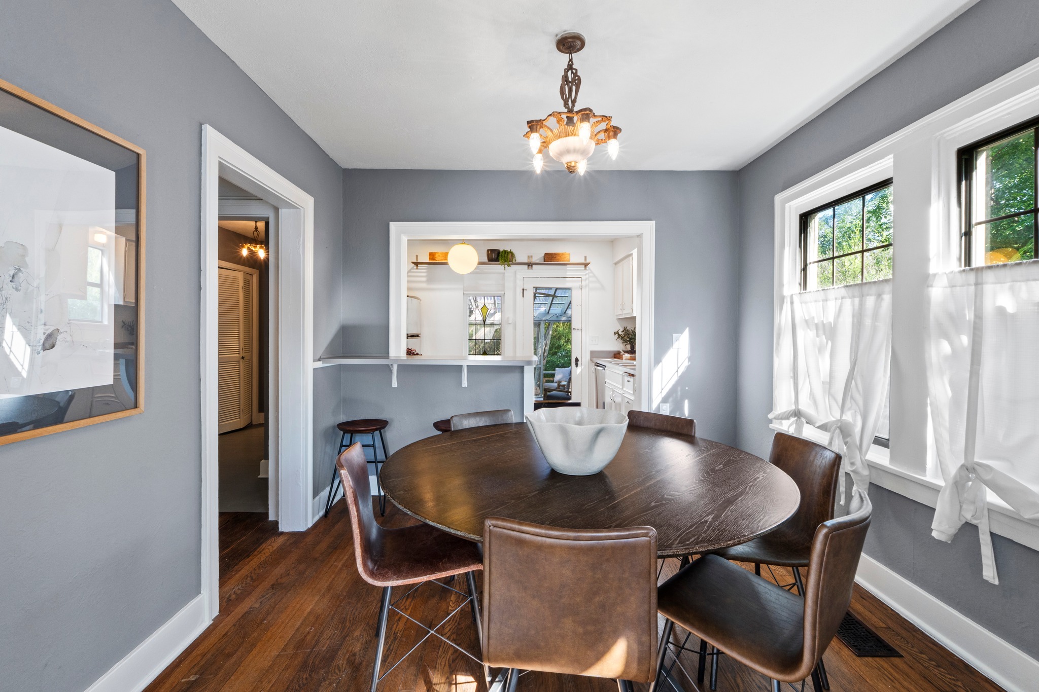 4802 Rowena Avenue Austin, TX 78751 - Photo 13 of 37 Dining area featuring original wood flooring, two large windows, a built-in pass-through window with a shelf, and an ornate light fixture.