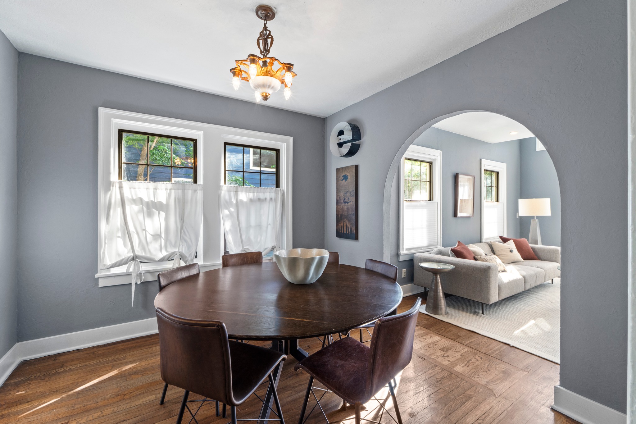 4802 Rowena Avenue Austin, TX 78751 - Photo 14 of 37 Original hardwood flooring throughout this dining space featuring gray walls, white trim, and a decorative antique chandelier.