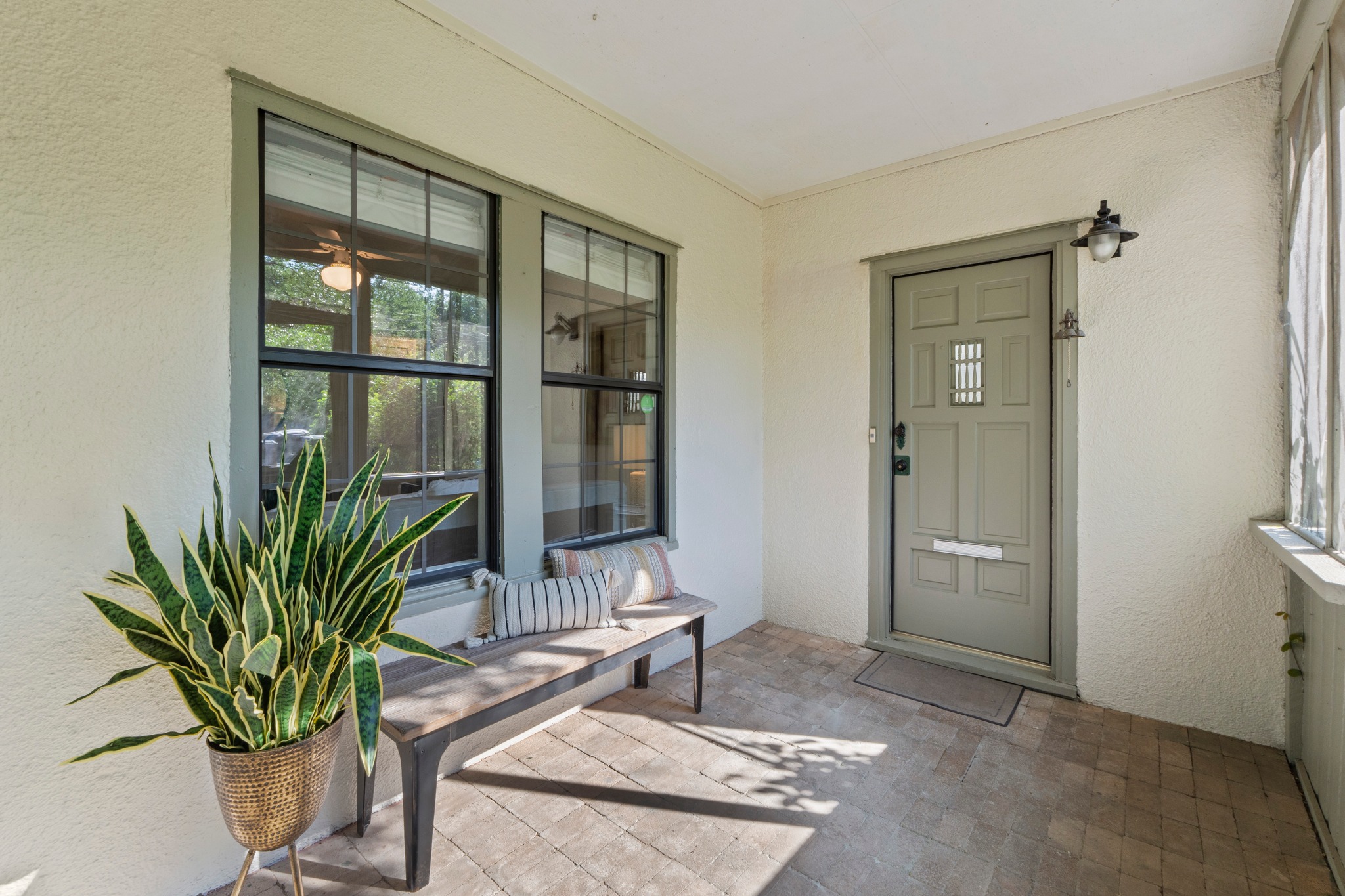 4802 Rowena Avenue Austin, TX 78751 - Photo 2 of 37 Covered entry porch featuring brick flooring, a paneled entry door with window, and a wall-mounted antique light fixture.