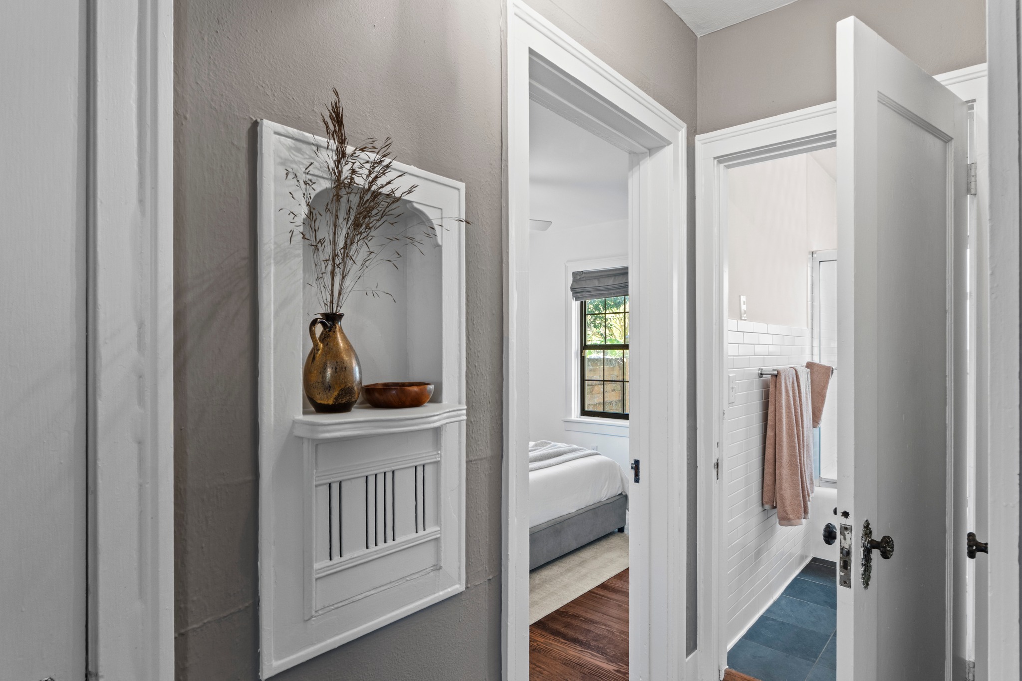 4802 Rowena Avenue Austin, TX 78751 - Photo 24 of 37 Hallway featuring a built-in arched niche, painted trim, and a bedroom entry with wood flooring