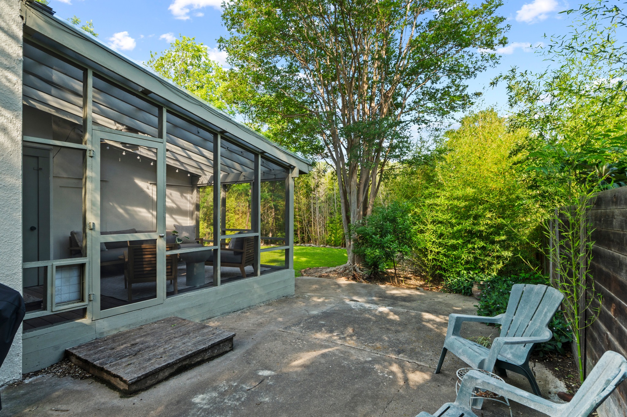 4802 Rowena Avenue Austin, TX 78751 - Photo 27 of 37 Concrete patio with a screened porch entry, surrounded by mature trees and lush landscaping.
