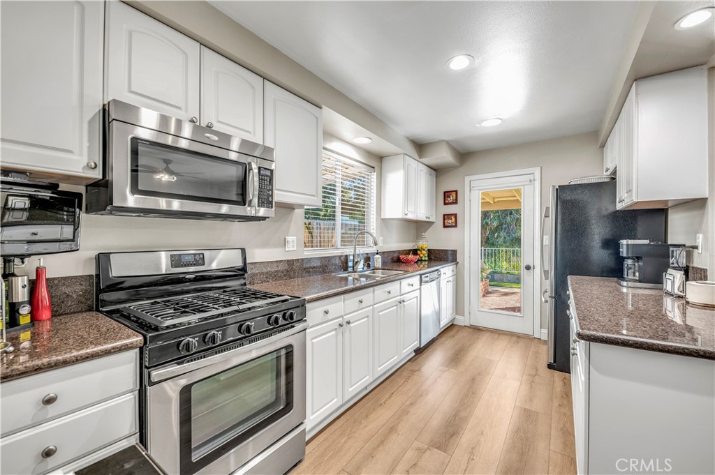 475 Termino Avenue Corona, CA 92879 - Photo 14 of 35 a kitchen with granite countertop a stove top oven a sink dishwasher a refrigerator and cabinets with wooden floor