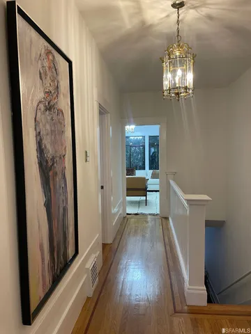 a view of a hallway with wooden floor and staircase