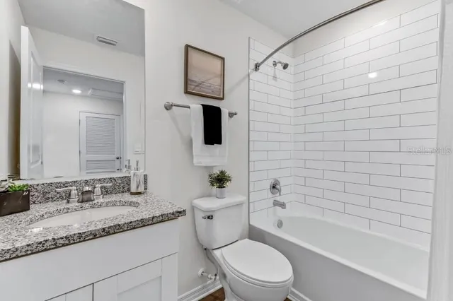 a bathroom with a granite countertop toilet a sink and bathtub