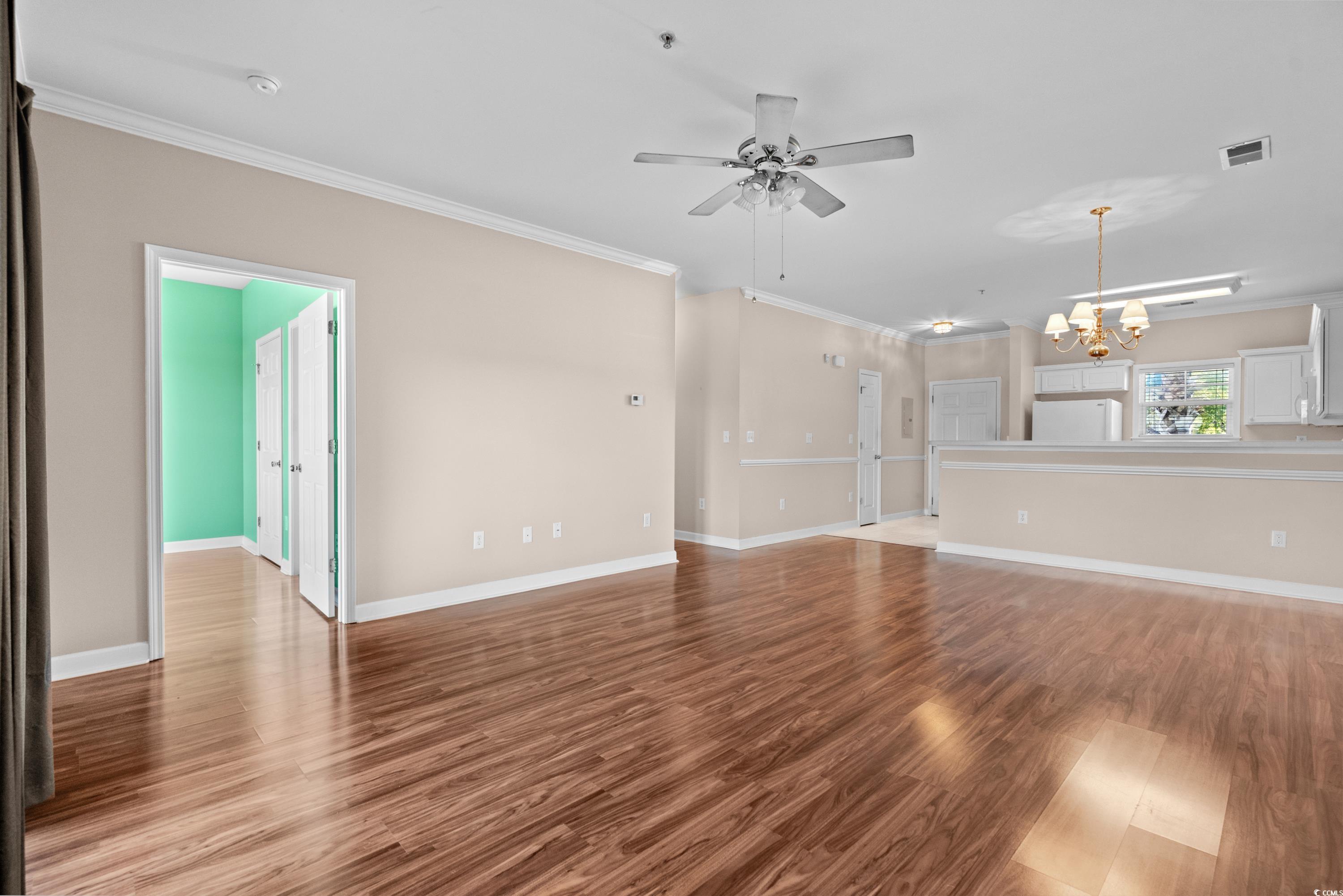 336 Kiskadee Loop, Unit B Conway, SC 29526 - Photo 10 of 40 Unfurnished living room with crown molding, ceiling fan with notable chandelier, and light wood-type flooring