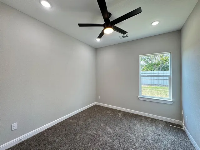 an empty room with a window and a fan