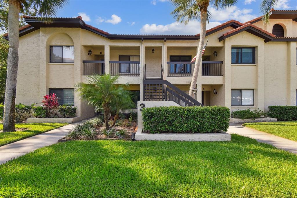 1801 East Lake Road South, Unit 3A Palm Harbor, FL 34685 - Photo 40 of 56 a front view of a house with a yard and potted plants