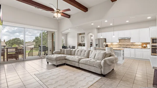 a living room with furniture and a large window with kitchen view