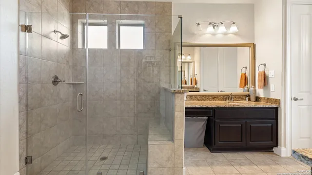 a bathroom with a granite countertop sink a mirror and a shower