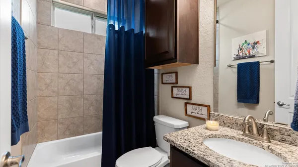 a bathroom with a granite countertop bathtub sink vanity mirror and toilet