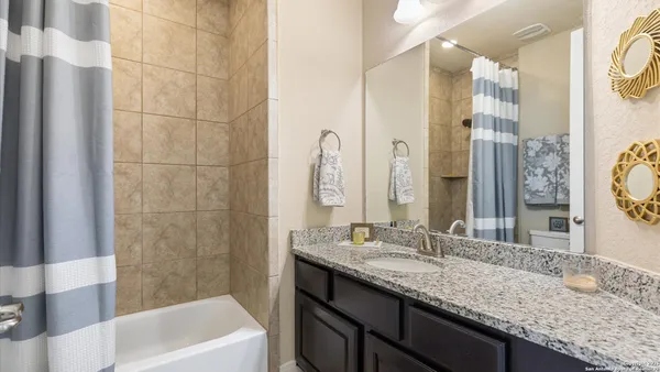 a bathroom with a granite countertop double vanity sink and a mirror