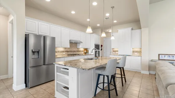 a kitchen with stainless steel appliances granite countertop a refrigerator a sink a stove a dining table and chairs