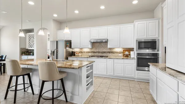a kitchen with kitchen island granite countertop stainless steel appliances and white cabinets
