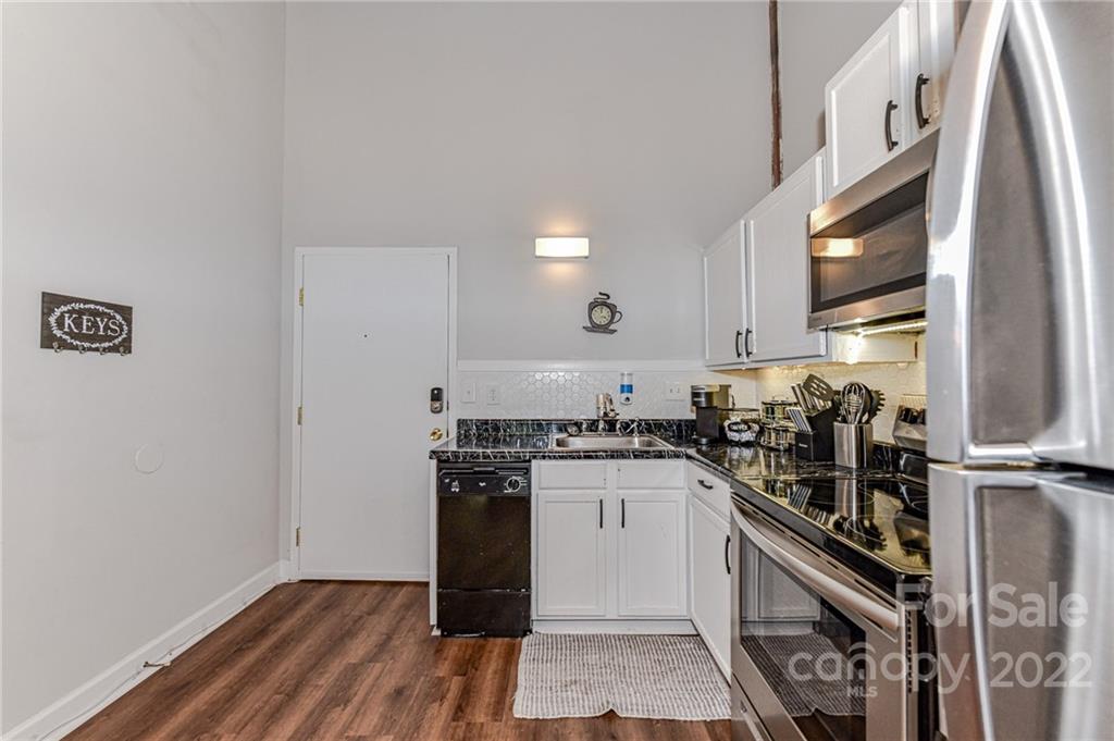 201 South Hoskins Road, Unit 106 Charlotte, NC 28208 - Photo 5 of 18 a kitchen with granite countertop a stove top oven and cabinets