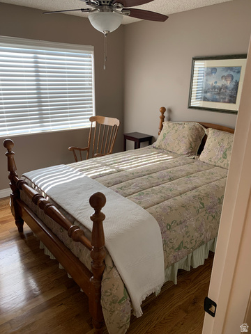 220 West Mill Road Ferron, UT 84523 - Photo 21 of 40 Bedroom featuring wood-finish flooring, a window with horizontal blinds, and a ceiling fan with light fixture
