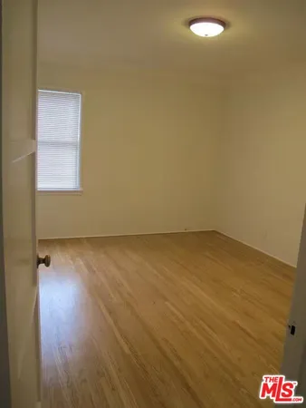 an empty room with wooden floor and fan