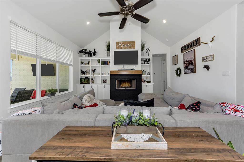 1040 Agnes Street North Springtown, TX 76082 - Photo 11 of 40 Living room featuring a warm lit fireplace, ceiling fan, and high vaulted ceiling