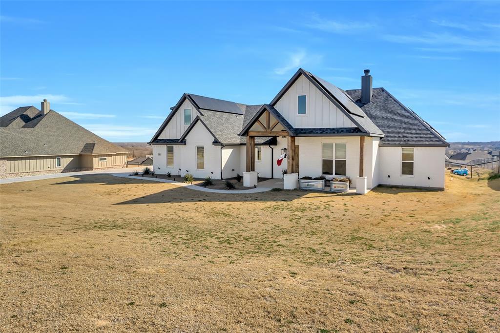1040 Agnes Street North Springtown, TX 76082 - Photo 35 of 40 Rear view of house featuring a chimney, a porch, board and batten siding, and roof with shingles