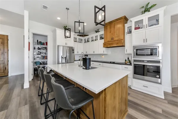 a kitchen with stainless steel appliances a stove a sink a microwave a refrigerator and cabinets