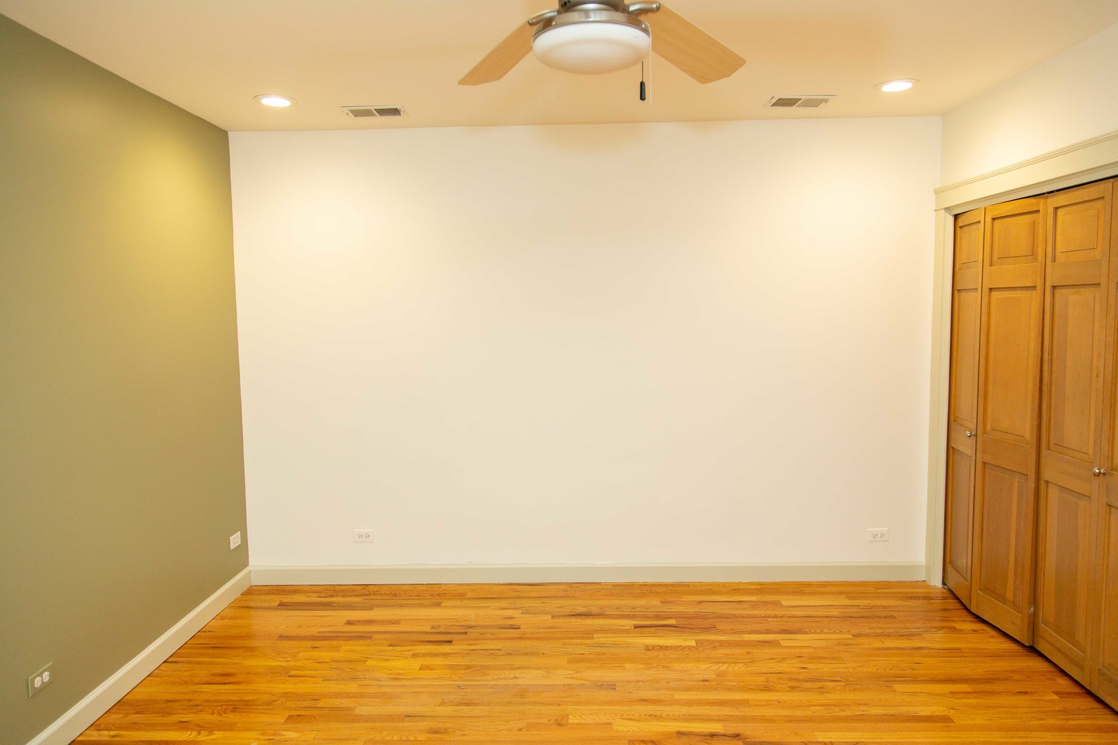 1607 Simpson Street, Unit 2E Evanston, IL 60201 - Photo 7 of 21 an empty room with wooden floor and fan