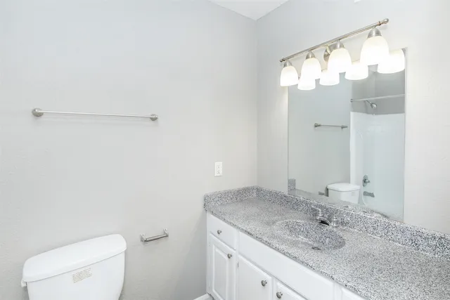 a bathroom with a granite countertop sink mirror and toilet