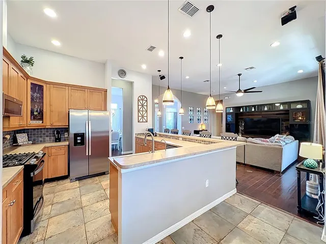 a kitchen with kitchen island a counter top space a sink stainless steel appliances and cabinets