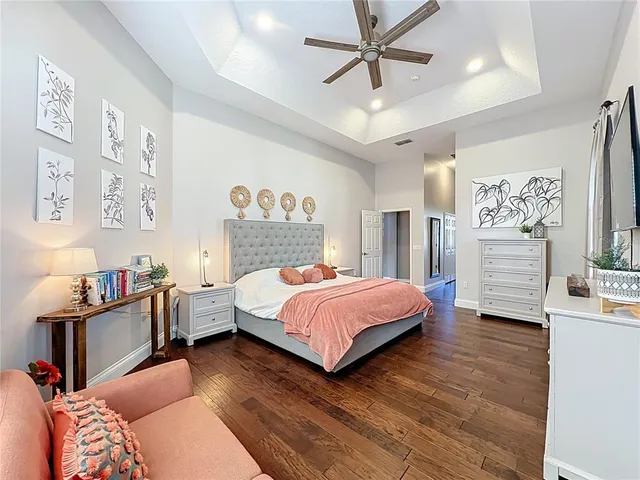 an empty room with wooden floor ceiling fan and windows