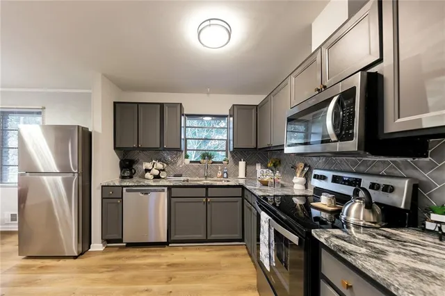 a kitchen with stainless steel appliances granite countertop a stove top oven a sink dishwasher a refrigerator and cabinets with wooden floor