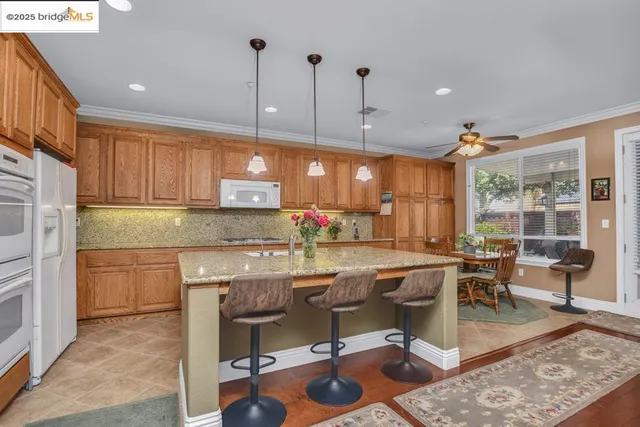 a kitchen with stainless steel appliances granite countertop a stove top oven a dining table and chairs with wooden floor