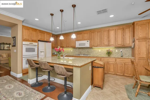 a kitchen with granite countertop kitchen island stainless steel appliances a stove a sink a oven a dining table and chairs