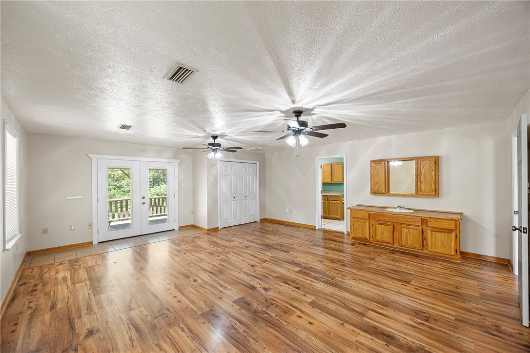 655 Charton Road Morrilton, AR 72110 - Photo 16 of 49 Spacious room featuring wood-finish flooring, two ceiling fans, and a built-in vanity with a single sink