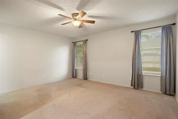 an empty room with chandelier fan and windows
