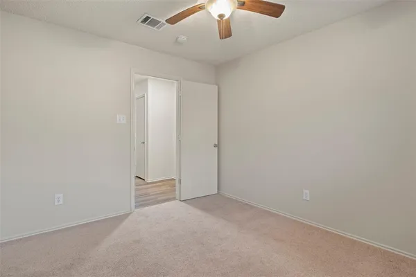 an empty room with a ceiling fan and carpet