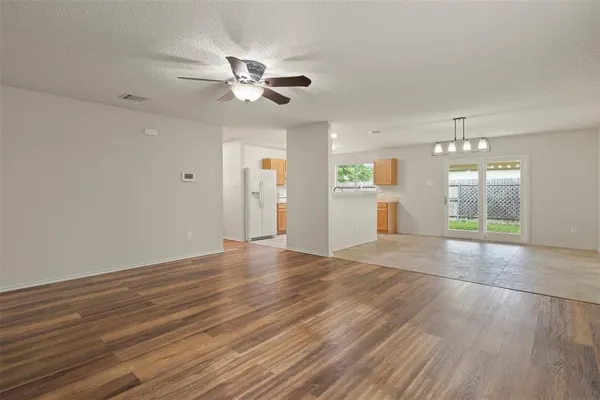 a view of an empty room with window and wooden floor