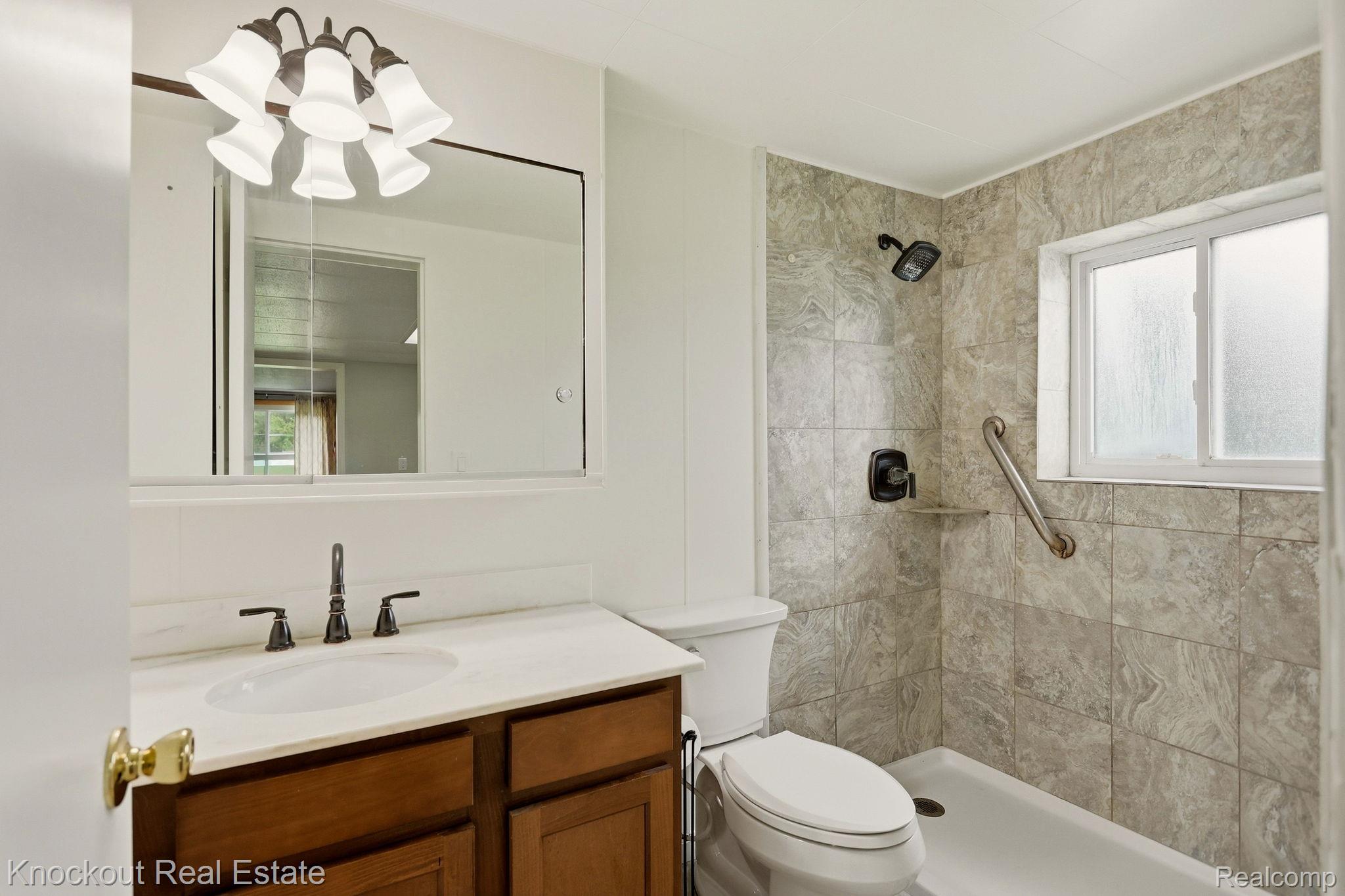 8771 Van Cleve Road Vassar, MI 48768 - Photo 18 of 44 Vanity with wood-finish cabinetry, white countertop, and dark-toned faucet
