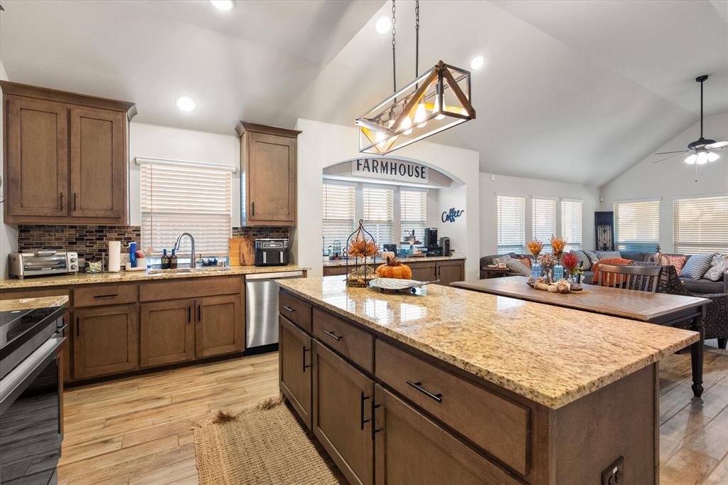 4021 Grove Valley Road Midlothian, TX 76065 - Photo 27 of 27 Kitchen featuring vaulted ceiling, light stone counters, backsplash, a kitchen island, and open floor plan