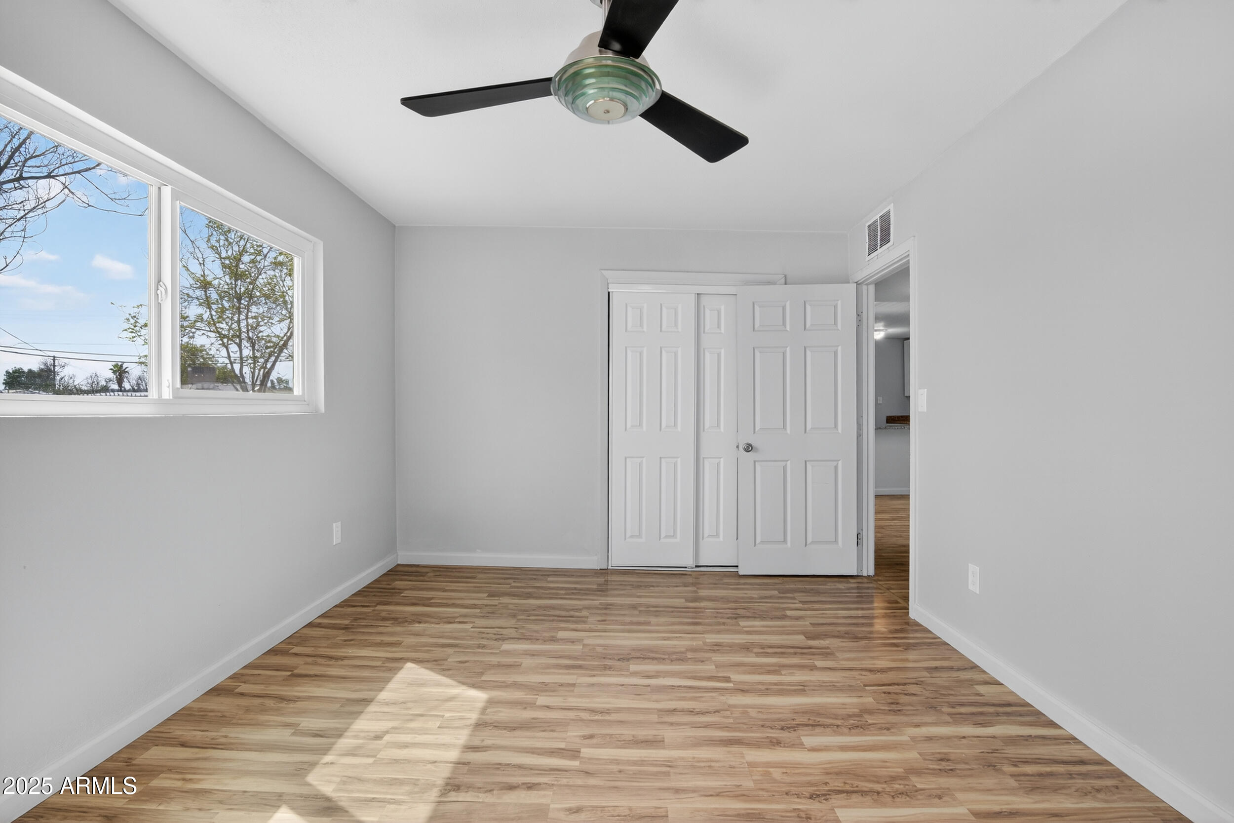 1410 South 24th Avenue, Unit A Phoenix, AZ 85009 - Photo 22 of 36 a view of an empty room with wooden floor and a window