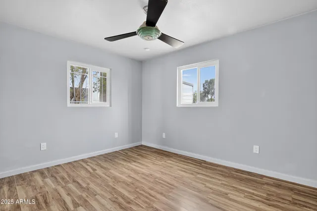 a view of empty room with wooden floor and fan
