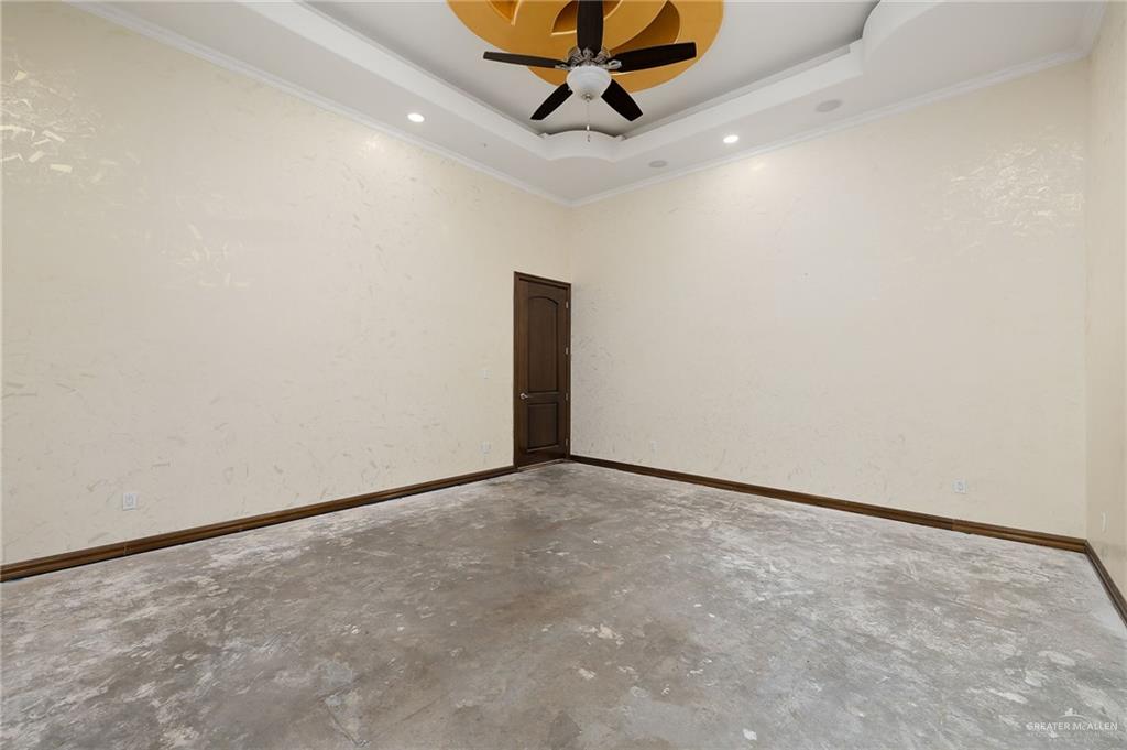 22111 Uresti Road Edinburg, TX 78542 - Photo 14 of 38 Tray ceiling with recessed lighting, brown ceiling fan, textured walls, and a paneled door